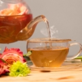 Glass teapot pouring through a tea strainer into a glass cup